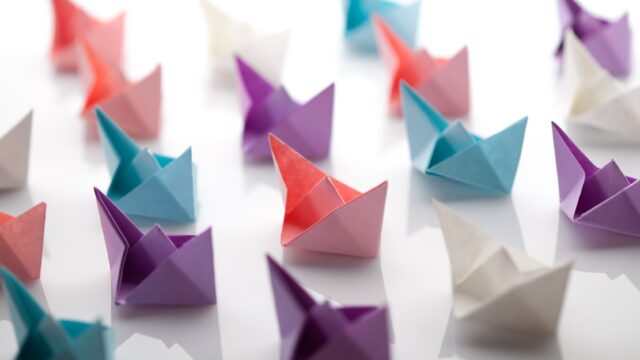 Leadership concept using paper ship among white